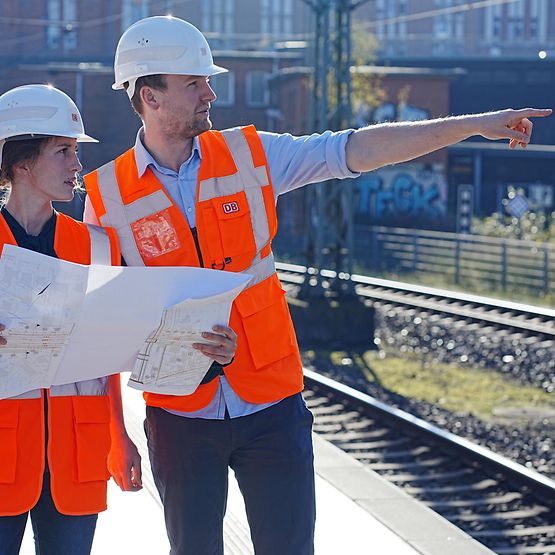 Mitarbeitende mit Bauplänen in der Hand