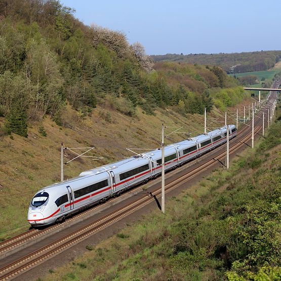 Der ICE 3neo auf der Fahrt durch eine Landschaft. 