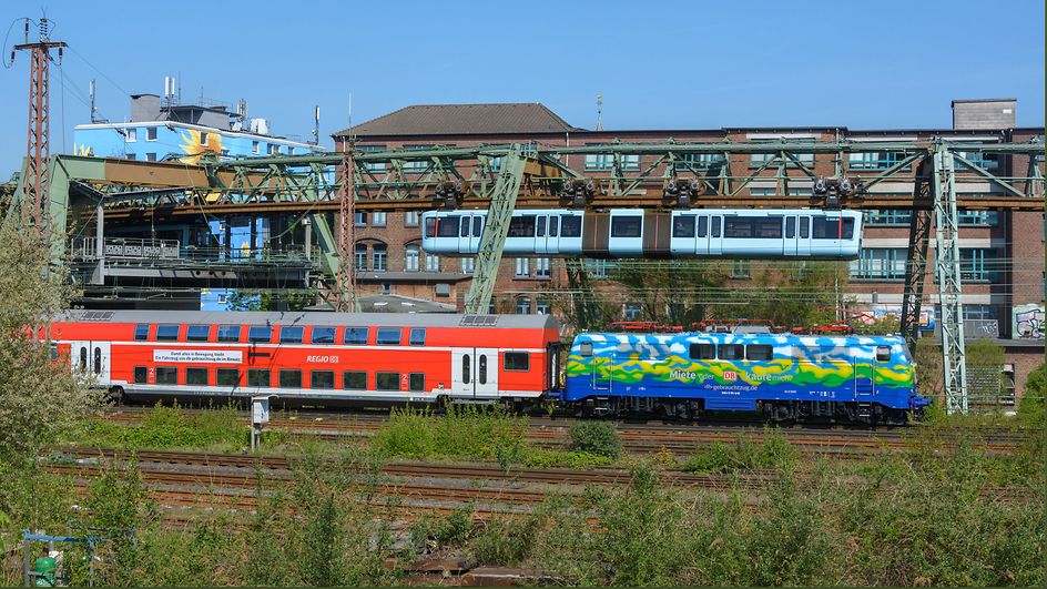 Begegnung zwischen Wuppertaler Schwebebahn und einer Regionalbahn mit Fahrzeugmaterial von DB Gebrauchtzug