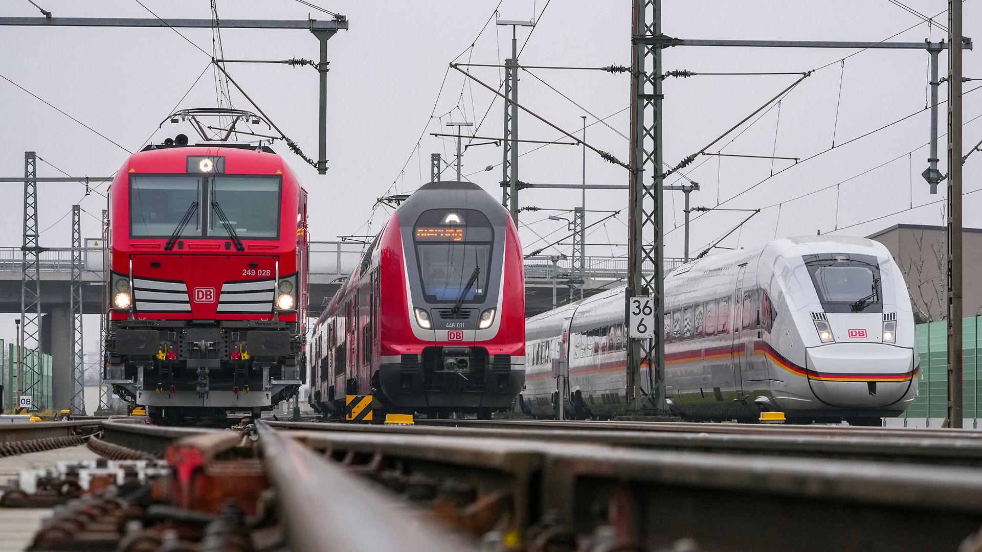 Drei Züge, ein Güterzug, ein Regionalzug und ein ICE, stehen auf der Riedbahn nebeneinander, frontal fotografiert