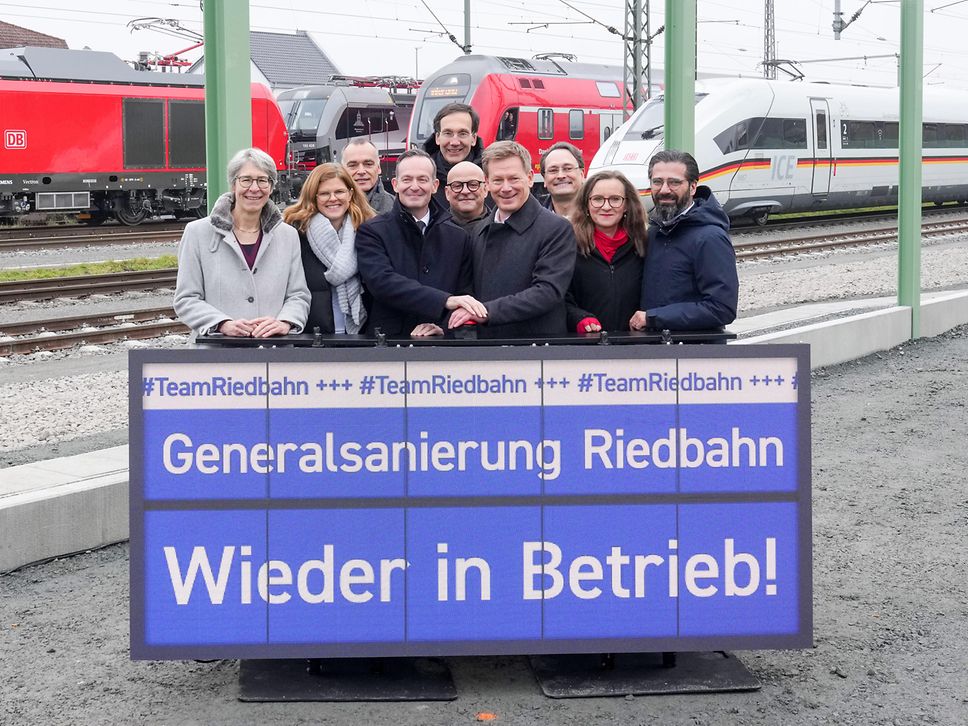 Gruppenfoto mit DB-Vorständen und Vertretern aus der Politik in Gernsheim, im Hintergrund drei Züge