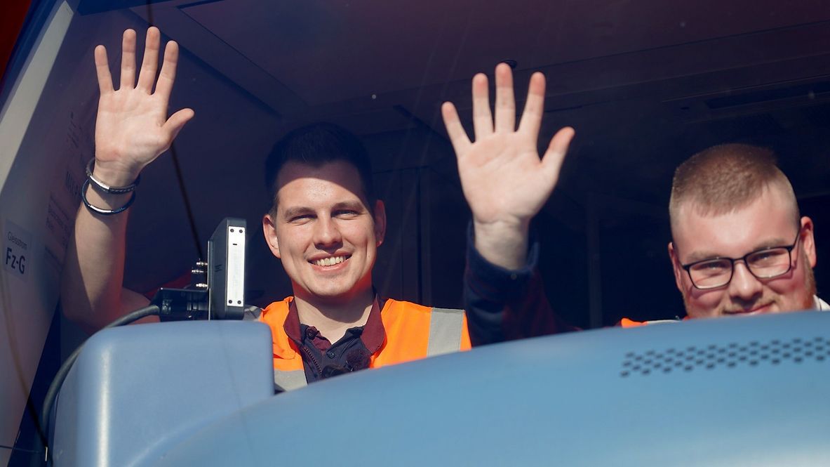 Eine Szene aus dem Film: Zwei DB-Mitarbeitende winken im Führerstand