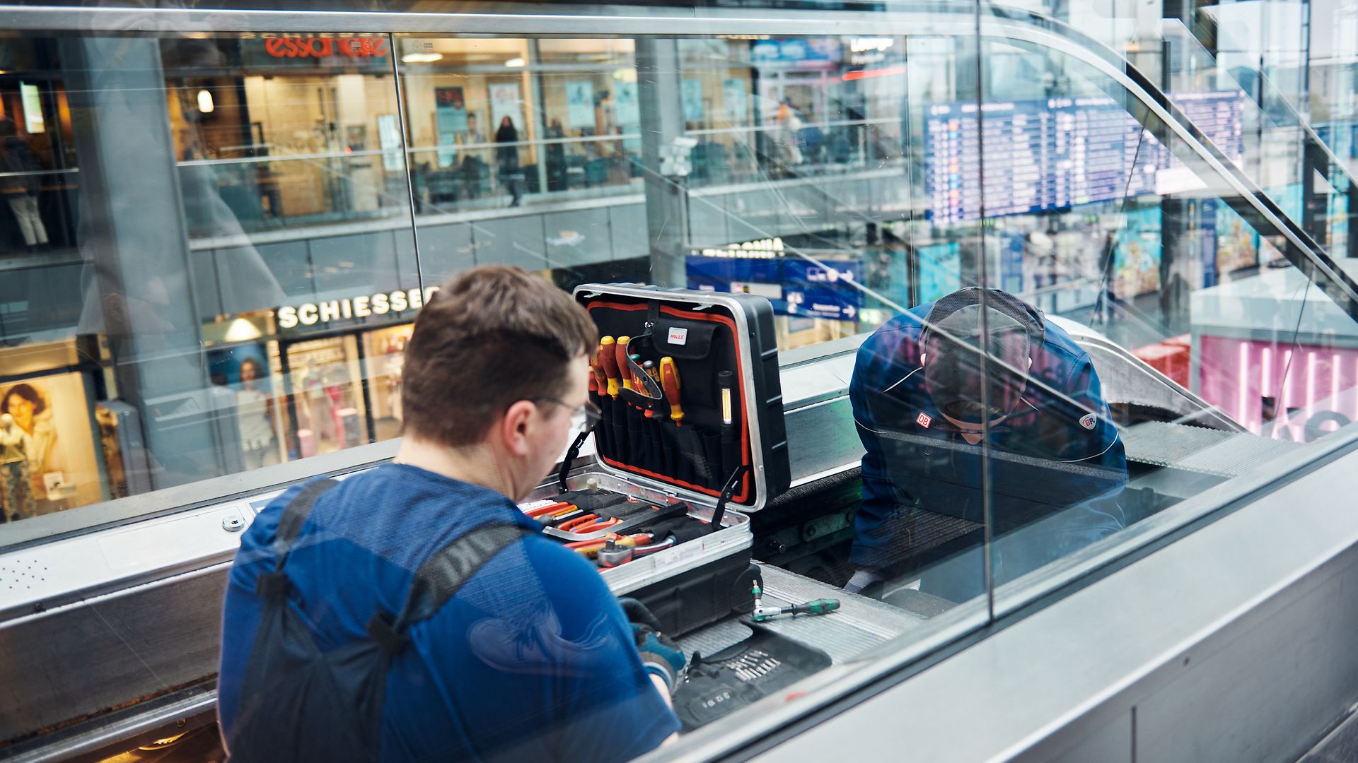Nahaufnahme zweier Techniker, die eine Rolltreppe reparieren