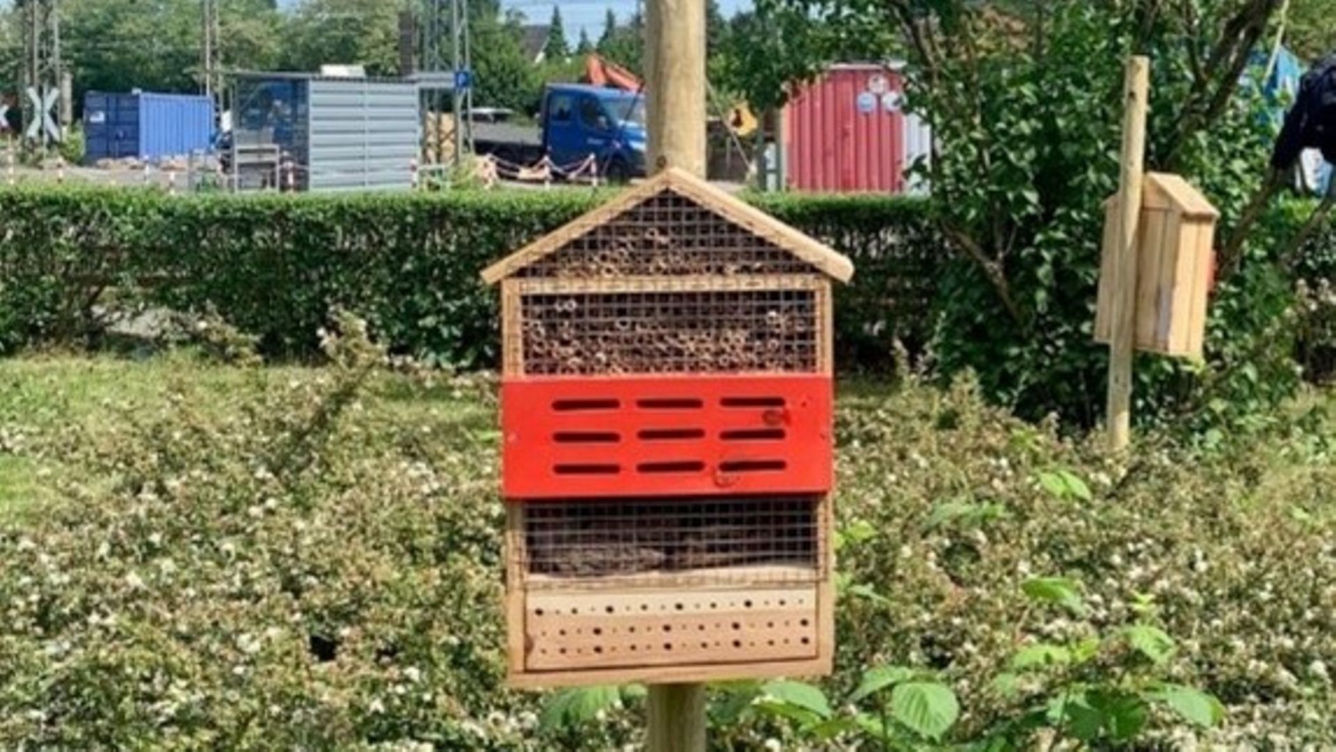 Ein Insektenhotel an einem Pfahl, im Hintergrund sind Teile des Werks zu sehen
